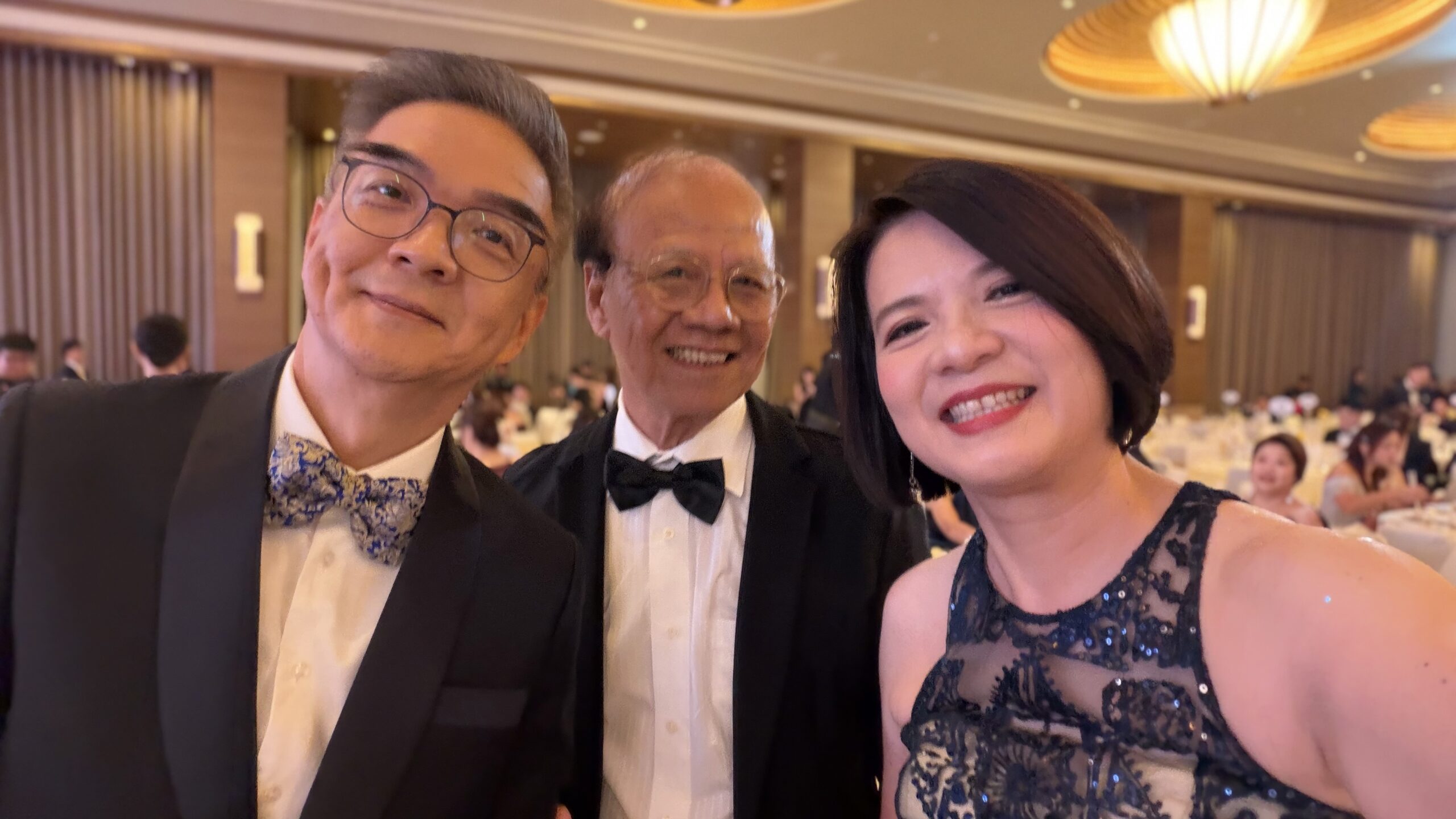 Three attendees smiling for a photograph in the gala ballroom.