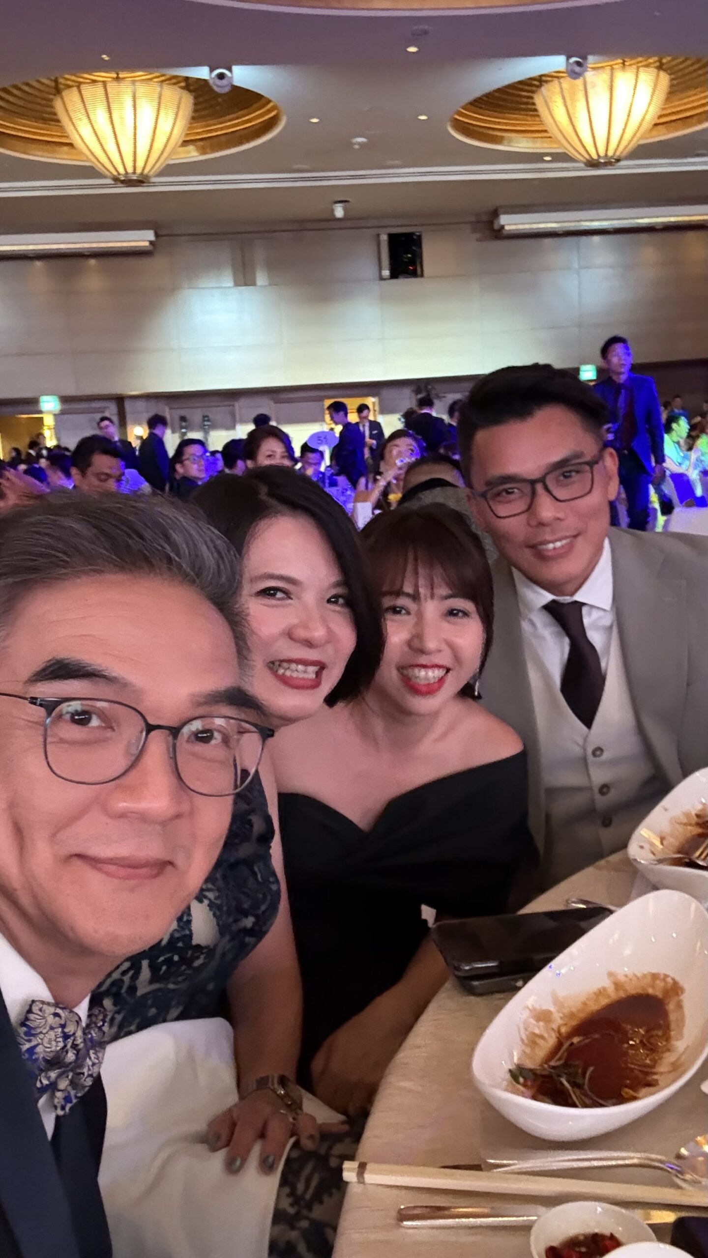 Four attendees taking a photograph together at a dinner table.